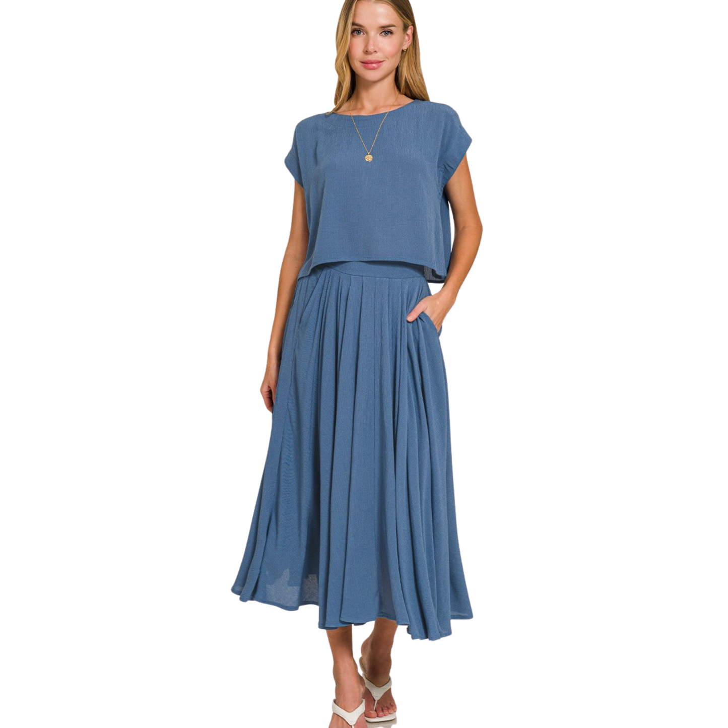 Elevate your casual wardrobe with this thoughtfully curated two-piece set from Zenana. The cropped short-sleeve tee pairs seamlessly with a midi skirt crafted from lightweight gauze fabric in a sophisticated dusty blue hue. The skirt's crinkled texture adds visual interest and movement, while the relaxed silhouette flatters multiple body types. Perfect for layering or wearing as-is, this set transitions effortlessly from weekend errands to relaxed social gatherings. Quality construction ensures durability t