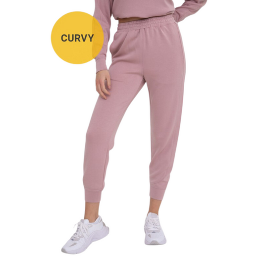 Our Curvy Joggers are designed with comfort and style in mind. Made from butter soft fabric in a neutral mauve color, they feature an elastic waistband, regular size, cuffed hem, and are crafted to flatter all body types. Feel confident and comfortable wearing these stylish joggers.