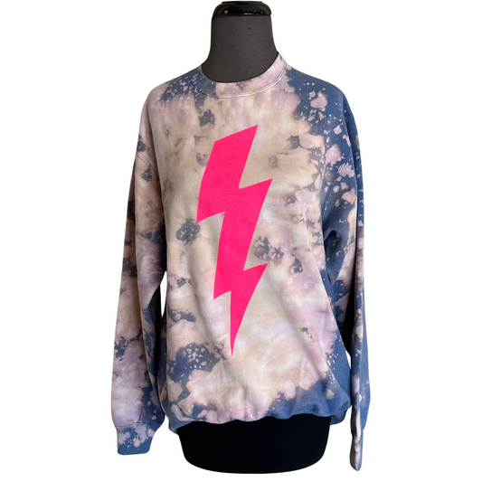 This Lightning Bolt Sweatshirt combines comfort and style. The unique bleach splatter and pink lightning bolt design make it an eye-catching item, and its long sleeve design is perfect for cooler days. Available in regular and plus size.