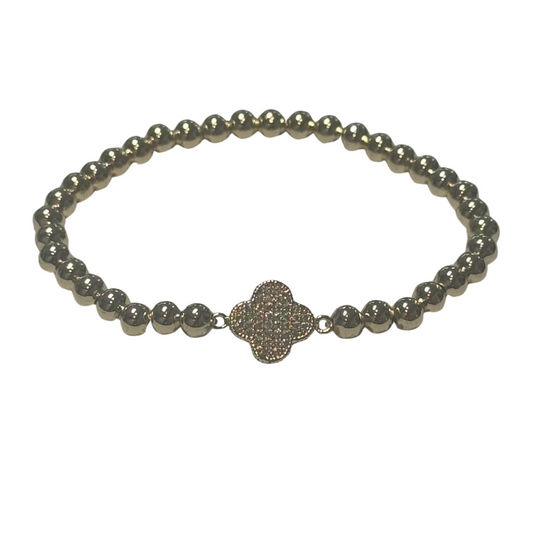 This elegant gold-toned stretchy bracelet features delicate beaded detailing and a distinctive clover accent, subtly embellished with sparkling rhinestones. Designed for a comfortable fit, it effortlessly combines style and versatility, making it an expert choice for adding a refined touch to any outfit.