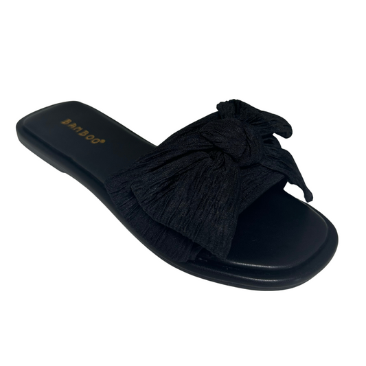 Expertly crafted, these black Woven Slides feature a comfortable flat sole and a stylish bow accent. Slip into this versatile footwear for a chic and effortless look.