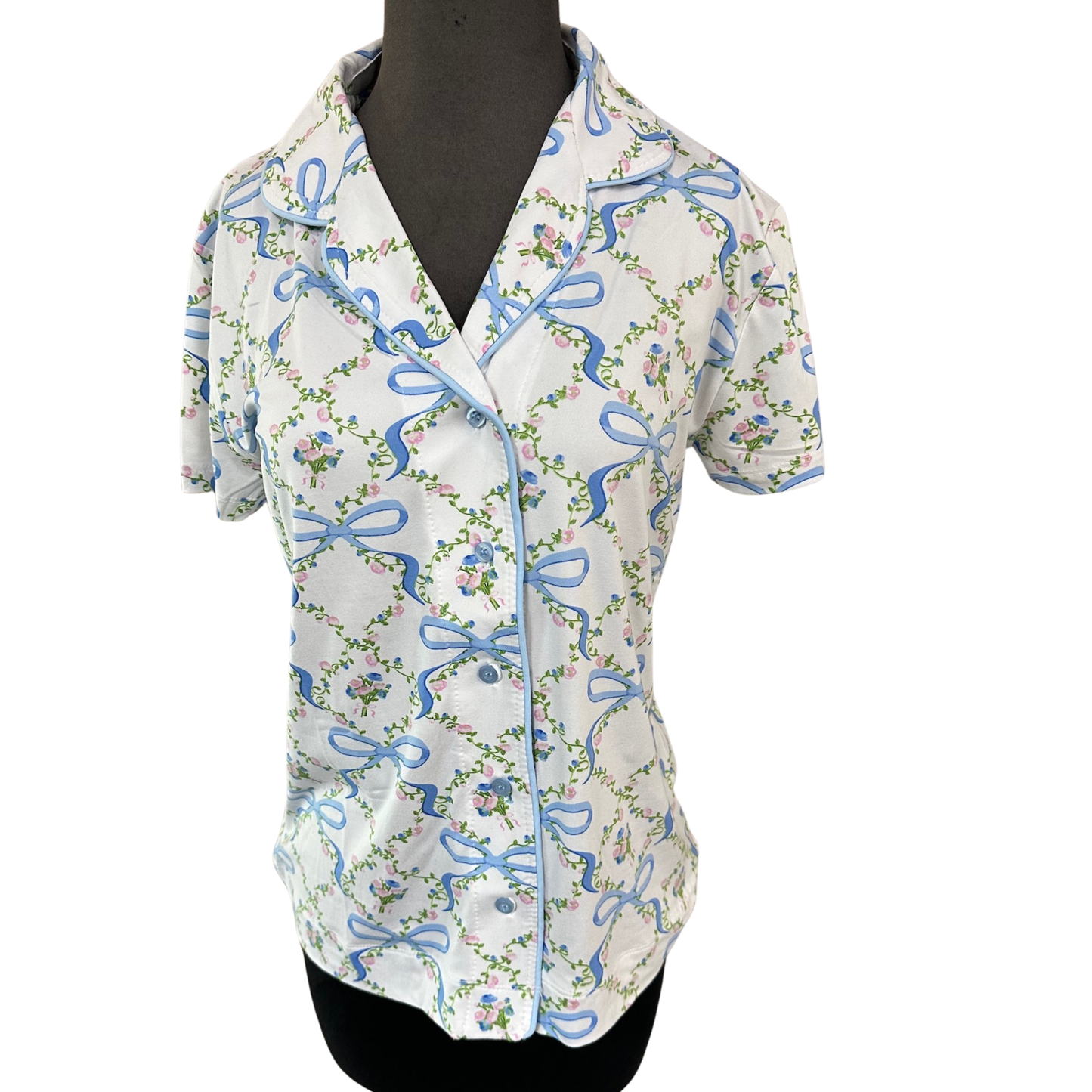 Blossom and bow print pajama top by Amanda Blu, crafted in soft white fabric with short sleeves and classic button-up closure. This charming design combines timeless floral motifs with delicate bow accents for a sophisticated sleepwear essential. The structured button front allows for easy dressing and layering versatility, while the relaxed fit ensures comfort throughout the night. Perfect for those who appreciate quality craftsmanship and refined details in their loungewear collection.