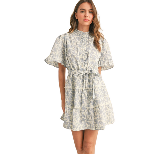 This light blue mini dress boasts a beautiful ruffle neckline and delicate floral pattern. With its button down design, it's both stylish and functional. Perfect for any occasion, this dress will make a statement with its elegant details.