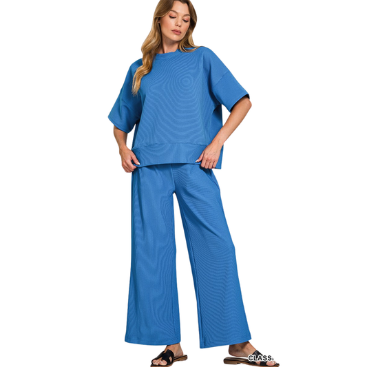 This classic blue Zenana set combines effortless style with everyday comfort. The short-sleeved top features a flattering round neckline and ribbed fabric that provides gentle stretch and shape retention. Paired with matching pants, this coordinated ensemble offers a polished, put-together look perfect for casual outings or relaxed workdays. The ribbed construction ensures durability while maintaining a refined appearance. An ideal choice for those seeking quality basics that transition seamlessly from day 