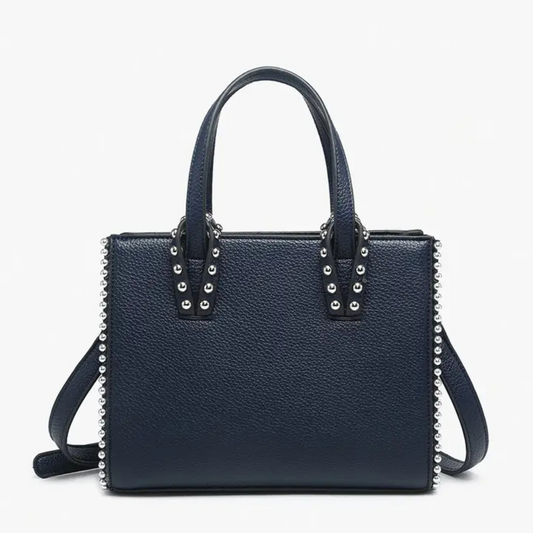 The Brenda Contrast Tote by Jen &amp; Co. features a sophisticated navy color with a studded design that adds a subtle edge to its classic look. This small purse offers versatility with a long attachable strap, allowing for comfortable crossbody or shoulder wear. Expertly crafted, it combines style and practicality for everyday use.