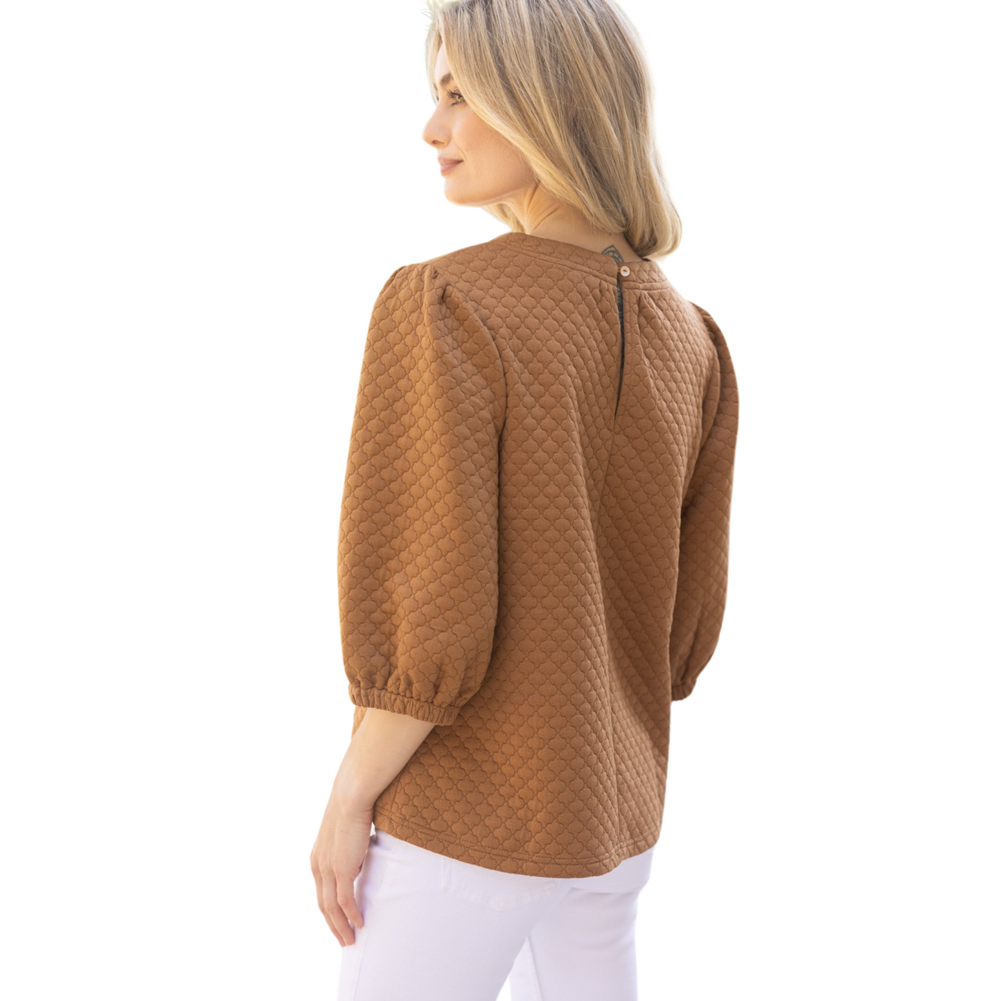 This quilted knit top features a round neckline with band and back neck button and elastic loop closure, paired with half puff sleeves for a fashionable and comfortable fit. In a warm camel color, this top is perfect for adding texture and style to any outfit.