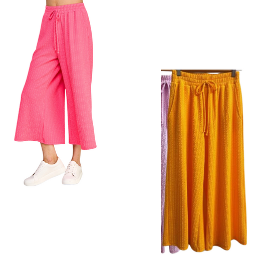 These Twist ribbed Capri pants are available in both neon orange and pink kosmos colors. Made of ribbed knit fabric, these capri pants provide a comfortable fit and stylish look. Perfect for any workout or casual day out.