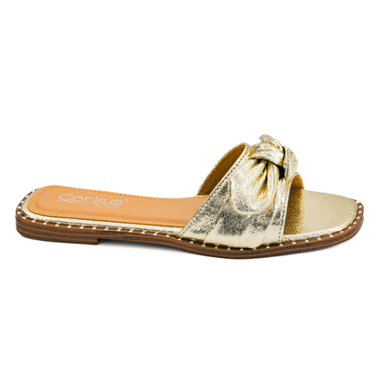 Elevate your warm-weather style with the Clam Bake, a stunning gold metallic open-toe sandal from Corkys. This flat sandal features a charming bow accent that adds a touch of feminine elegance to any outfit. Perfect for casual days, beach trips, or evening strolls, the Clam Bake combines comfort with eye-catching metallic shine. The open-toe design keeps your feet cool while the flat sole provides all-day wearability. A versatile essential that transitions effortlessly from day to night.