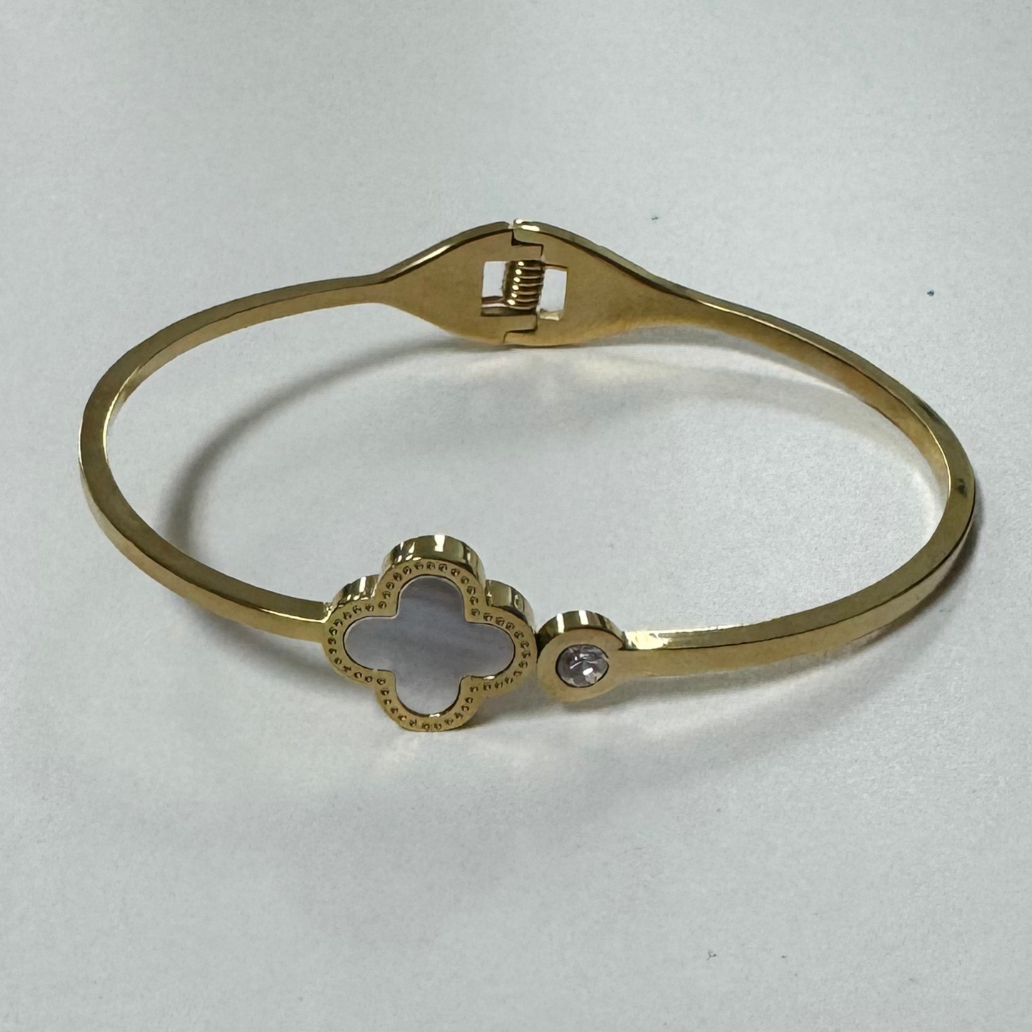 This elegant bangle features a delicate clover design and sparkling rhinestone accents, making it the perfect accessory for any occasion. Crafted in gold, it adds a touch of sophistication to any outfit. With its cuff design, this bangle is easy to wear and adds a touch of glamour to any ensemble.