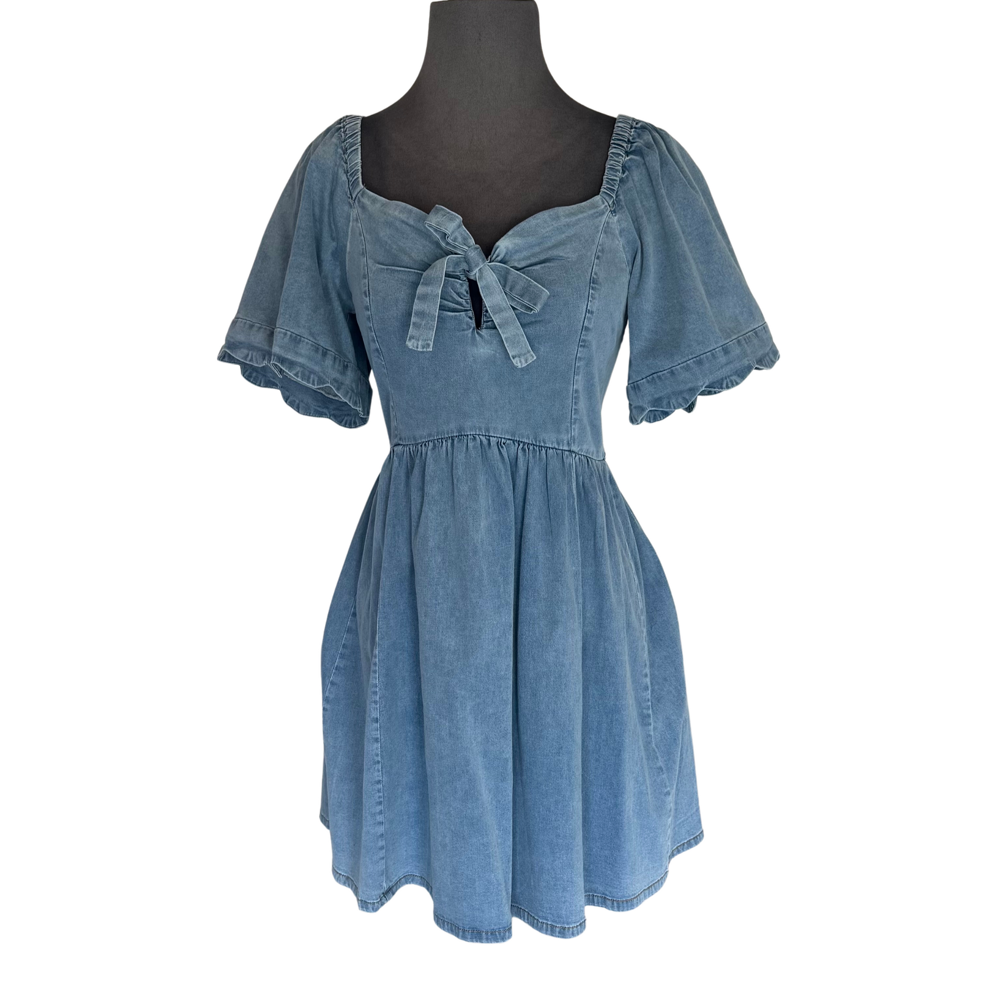 Stay on trend with the Umgee Denim Scalloped Sleeve Dress. The chic denim color and smocked back provide both style and comfort. Short sleeves, a mini length, and a bow accent add a touch of femininity. A must-have for any fashion-forward wardrobe.