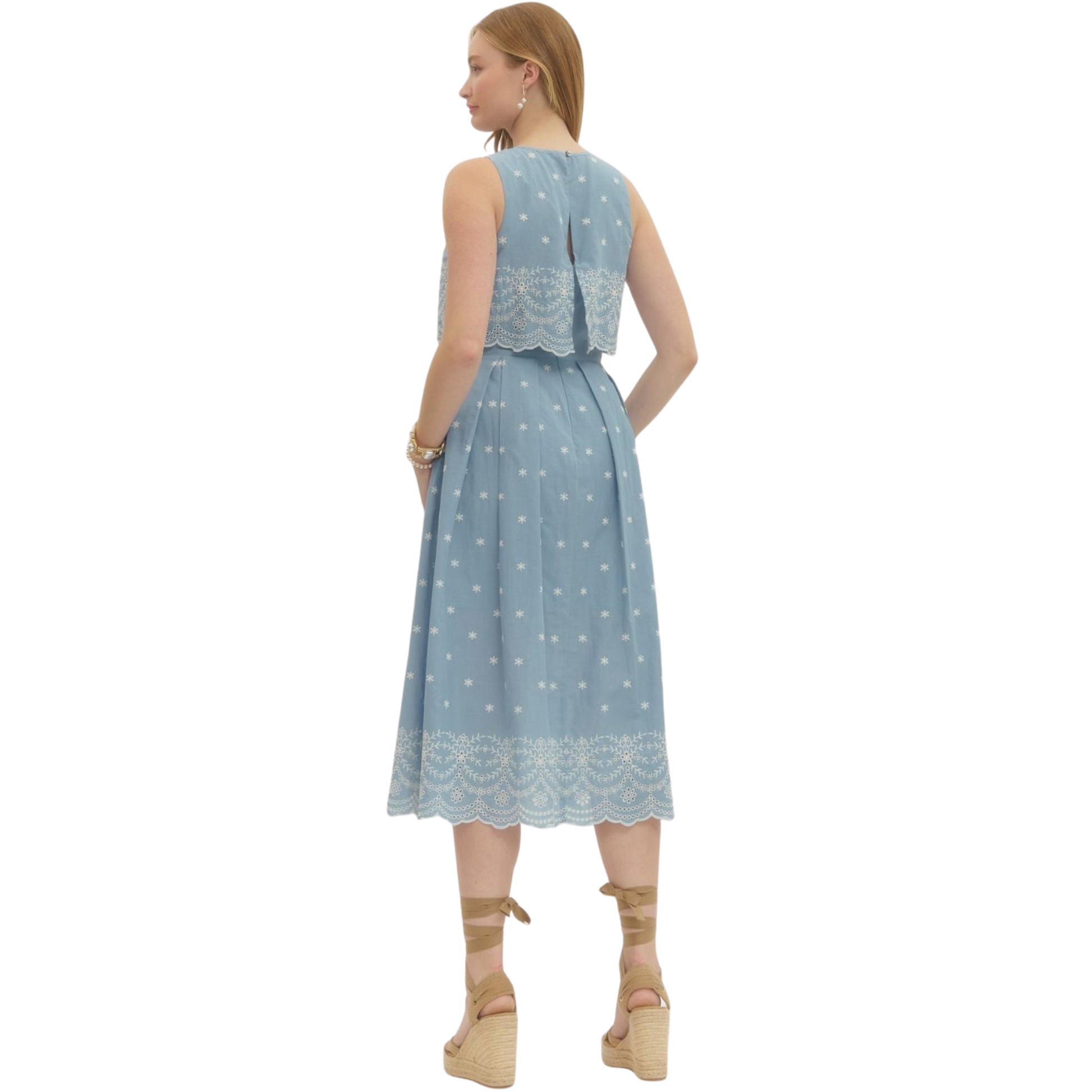 This Entro midi dress combines effortless elegance with thoughtful design details. The light blue fabric provides a versatile canvas for the intricate embroidery that adorns the piece, adding visual interest and sophistication. The sleeveless silhouette offers breathability and a modern aesthetic, while the midi length ensures a polished, refined look suitable for various occasions. Whether styled casually with sneakers or dressed up for an event, this dress delivers both comfort and contemporary style.