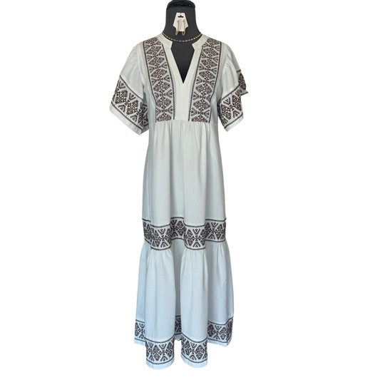 This elegant white v neck midi dress is adorned with intricate brown aztec embroidery and features delicate flutter sleeves. Perfect for any occasion, this dress adds a touch of sophistication and charm.