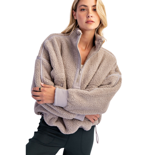 Experience ultimate warmth and style with the Rae Mode Mock Neck Sherpa Jacket. Crafted in a versatile taupe shade, this quarter-zip pullover features plush sherpa fabric that provides exceptional comfort and insulation. Its mock neck design offers added protection against chilly winds, making it ideal for layering in colder weather. Perfect for both casual outings and outdoor adventures, this jacket combines cozy softness with functional style for reliable all-day wear.