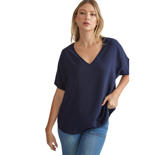 This navy solid v-neck top features an asymmetric rounded hem detail that adds a unique touch to any outfit. Made with lightweight, semi-sheer woven fabric, this top is perfect for all-day wear. Look effortlessly stylish and feel comfortable at the same time.