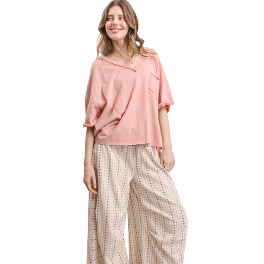 Effortless style meets comfort in this oversized v-neck top from Blue Velvet. The relaxed silhouette drapes beautifully while the short sleeves keep things breezy and casual. Rendered in a soft pink coral hue, it's the perfect layering piece or standalone statement. Pair with your favorite jeans or linen pants for an understated, put-together look that works from day to night.