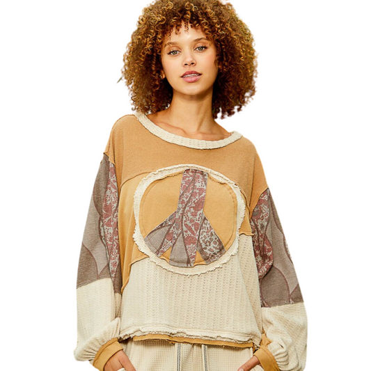 This Long Sleeve Peace Emblem Top is designed for comfort and style. Its oversized fit and round neck make it a cozy choice for any season. The latte color and thermal print give it a modern touch, while the patchwork and frayed edge details make this top unique.