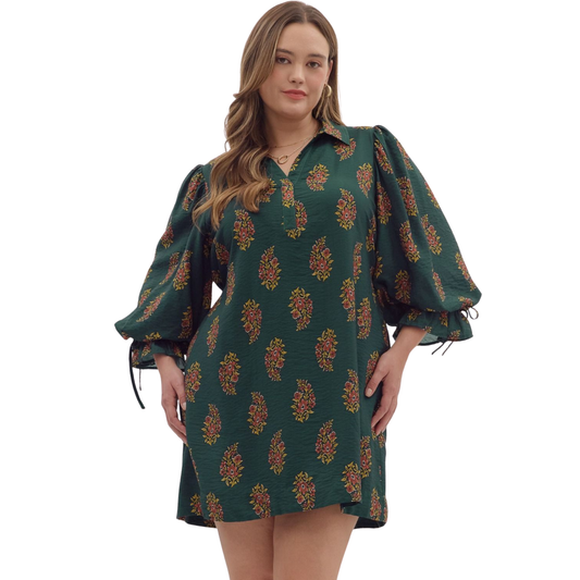 This Entro puff sleeve mini dress in a rich hunter green features an eye-catching abstract print designed to flatter plus-size figures. Its playful puff sleeves and mini length combine style with a comfortable fit, making it ideal for both casual and dressier occasions. The dress offers a confident silhouette while showcasing unique design details that highlight your curves effortlessly. Perfect for those who appreciate bold fashion with a tailored touch.