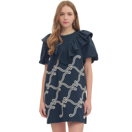 Navy mini dress by Entro featuring a charming ruffle trim yoke and short puff sleeves. This playful silhouette combines feminine details with a flattering fit, perfect for casual outings or dressed-up occasions. The puff sleeves add a touch of vintage-inspired charm while the ruffle trim yoke creates visual interest at the neckline. Ideal for spring and summer styling.