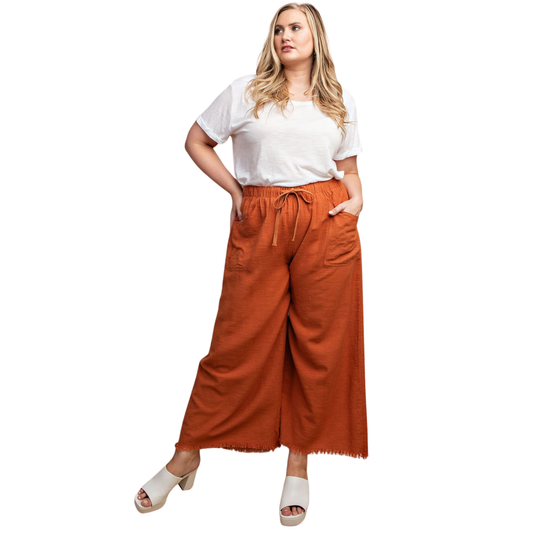 Elevate your wardrobe with these GiGio Frayed Wide Leg Pants in a rich red clay hue. Designed for plus-size figures, these pants offer a flattering silhouette with a relaxed wide-leg cut that moves beautifully. The frayed hem adds an effortless, on-trend detail, while functional pockets keep your essentials close. Perfect for casual outings or dressed-up occasions, this versatile piece combines comfort and style.