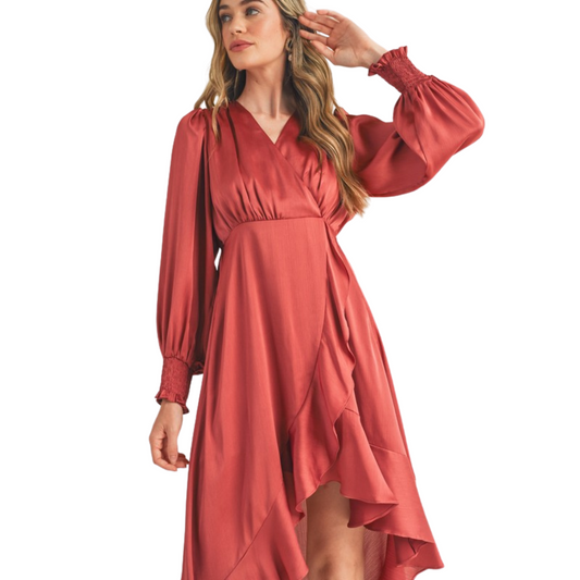 Look stunning in this ruffled hi-low midi dress crafted from a satin effect fabric with a flattering surplice neckline, long puff sleeves with smocked cuffs, and ruffle trim for a feminine finish. The high-low hem adds a timeless touch in the sophisticated rose vale color.