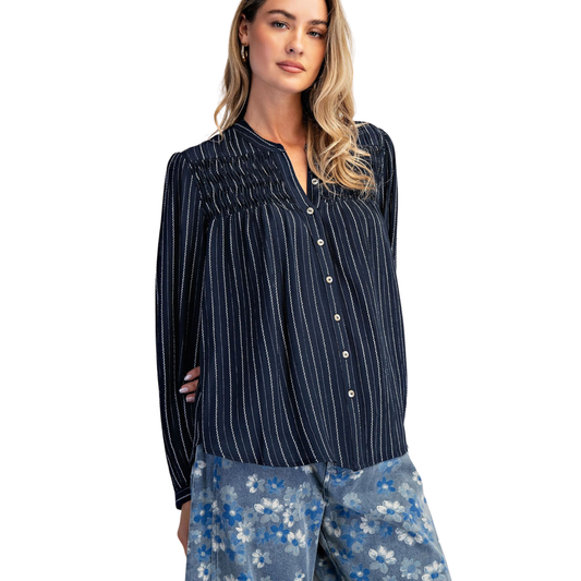 Elevate your wardrobe with this navy Cotierra button-down blouse, featuring timeless vertical stripes and a flattering smocked design. The structured smocking adds dimension and comfort, while the classic striped pattern pairs effortlessly with any bottoms. Perfect for work, weekend outings, or layering. A versatile essential that transitions seamlessly from season to season.