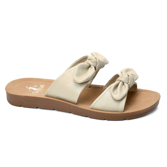 The Take a Bow sandals by Corkys are the perfect addition to your summer wardrobe. With a stunning gold metallic finish and delicate bow accents, these flat sandals add a touch of elegance to any outfit. Stay stylish and comfortable all season long with the Corkys brand.