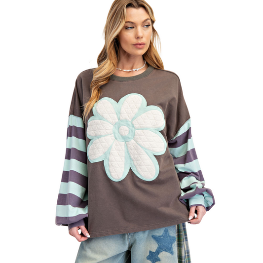The Flower Patch Terry Knit Pullover by Easel features a refined dark grey base accented with a blue flower patch design, offering a subtle yet stylish statement. Crafted with long sleeves, this pullover combines comfort and warmth with a polished look, making it perfect for layering in cooler weather or as a standout piece on its own. Its quality knit fabric ensures durability and a gentle feel against the skin, ideal for those who appreciate blend of design and functionality in their wardrobe.