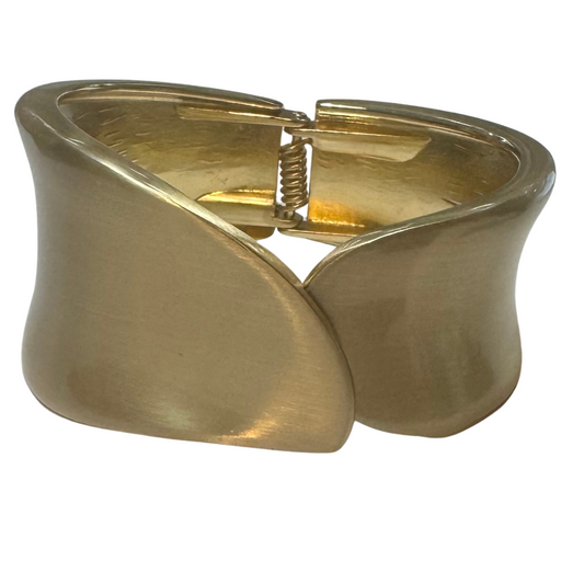 This thick cuffed bangle bracelet features a hinged design for easy wear and removal. Crafted in gold, it offers a bold yet refined statement piece that complements both casual and formal attire. Its sturdy construction ensures durability while maintaining a sleek, polished look suitable for everyday elegance.