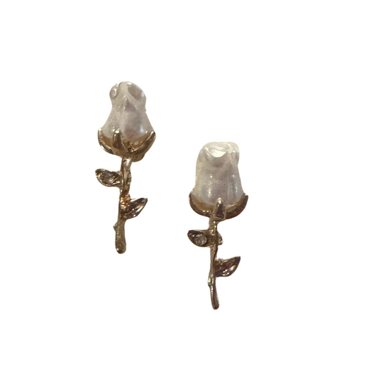Crafted with a luxurious gold finish, these Rosebud Stud Earrings feature a delicate white rose design. Perfect for adding a touch of elegance to any outfit, these stud earrings are a must-have for any jewelry collection. Enjoy the timeless beauty and versatility of these stunning earrings.