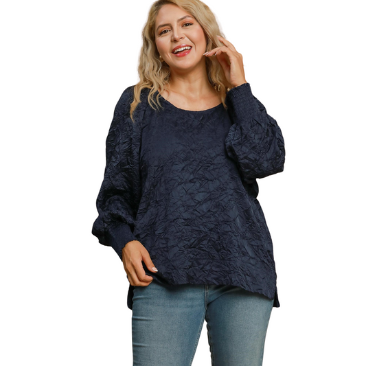 Introducing the Umgee Brand Wrinkled Round Neck Top. This top features a navy color and a unique crinkled pattern to add texture and dimension. Its long, cuffed sleeves are perfect for cooler weather. Designed specifically for plus size individuals, this top is a stylish and comfortable addition to any wardrobe.